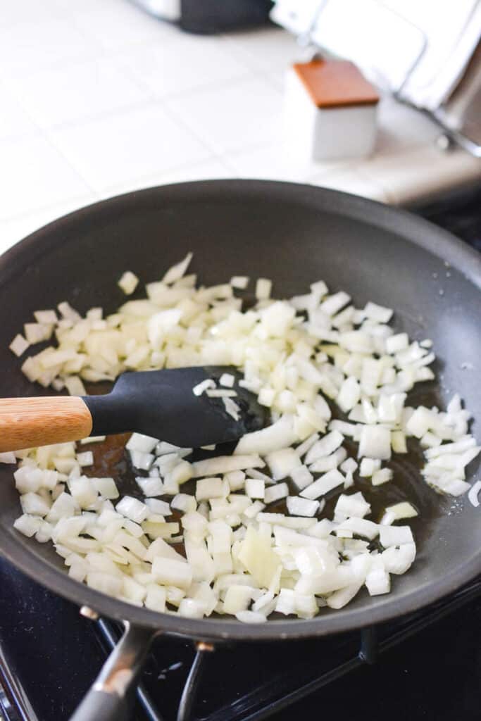 Onions and garlic being sauteed in a pan.