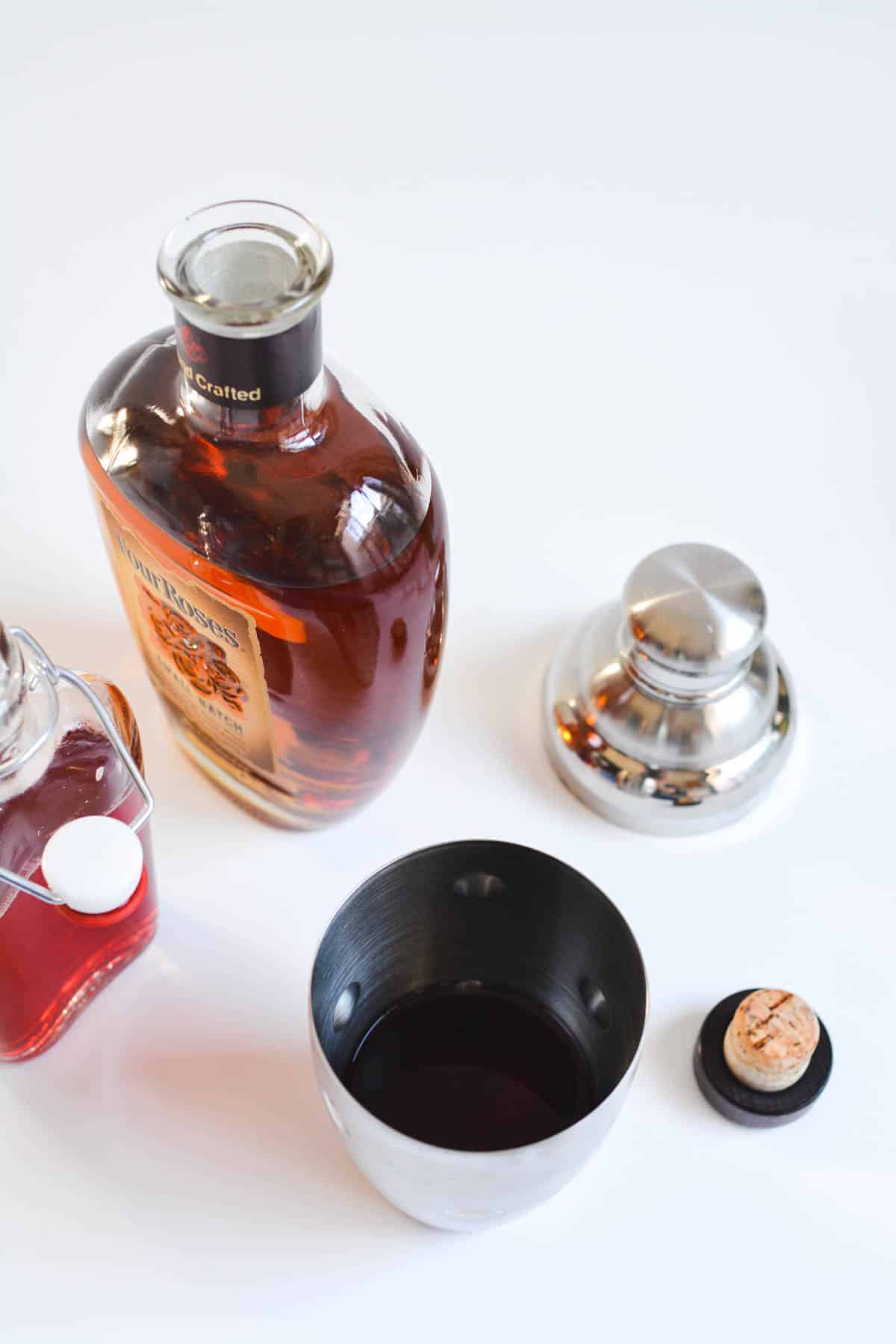 Cocktail shaker on a table with cocktail ingredients.