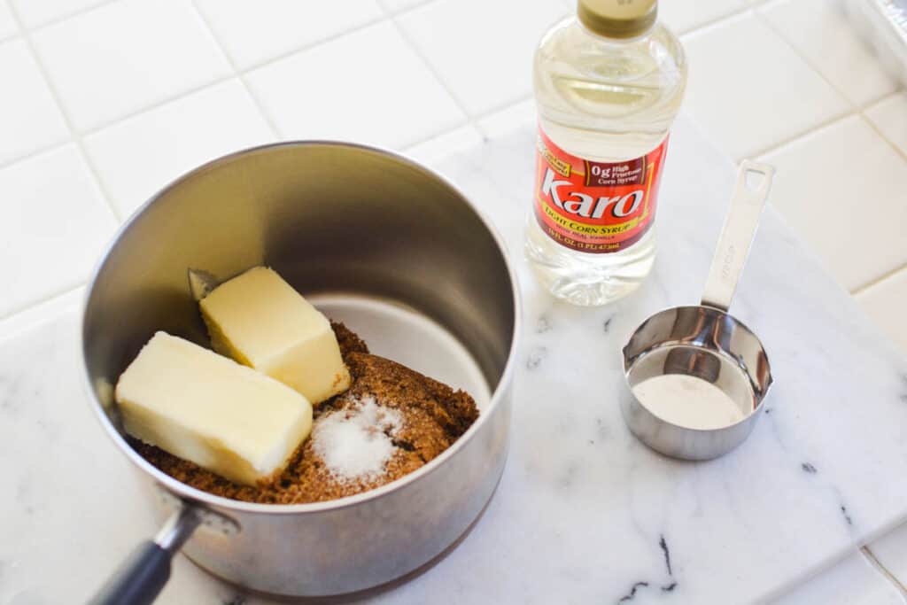 Butter, sugar and salt in a saucepan on a counter next to corn syrup.