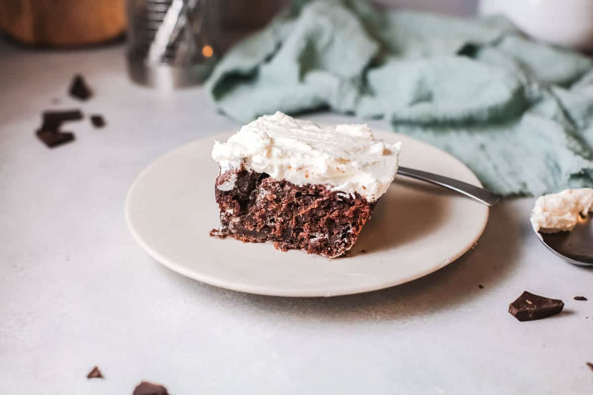 A serving of chocolate cake topped with white frosting on a plate.