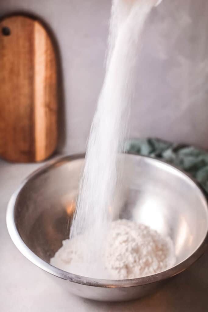 Sugar being poured into a bowl to make a cake.