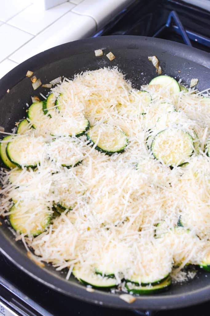 Sauteed zucchini in a pan topped with parmesan cheese.