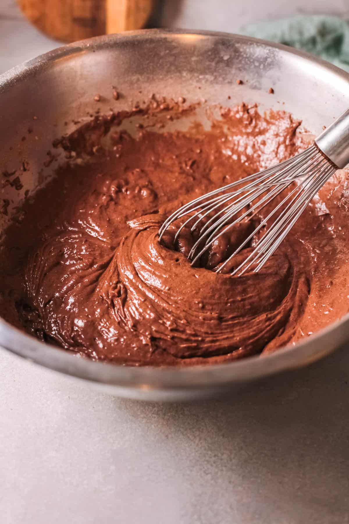 Mixed chocolate cake batter in a bowl with a whisk.