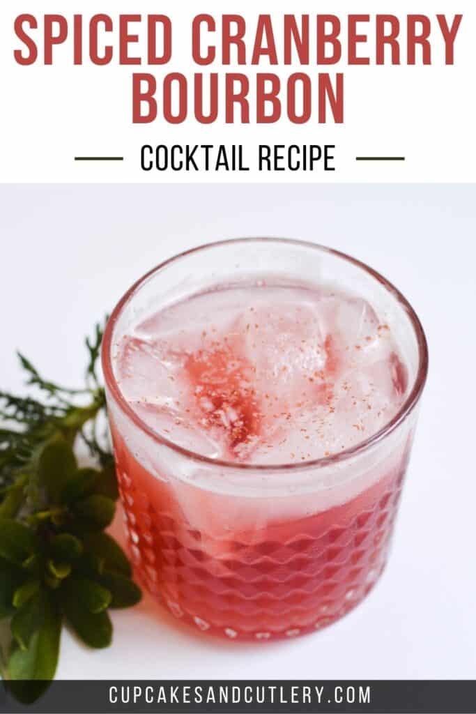 Spiced Cranberry Bourbon Cocktail Recipe in a glass with greenery along side.