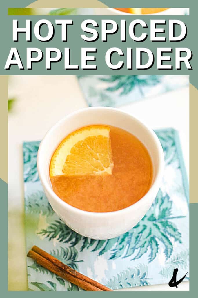 Close up of a white mug with hot apple cider on a napkin on a table.