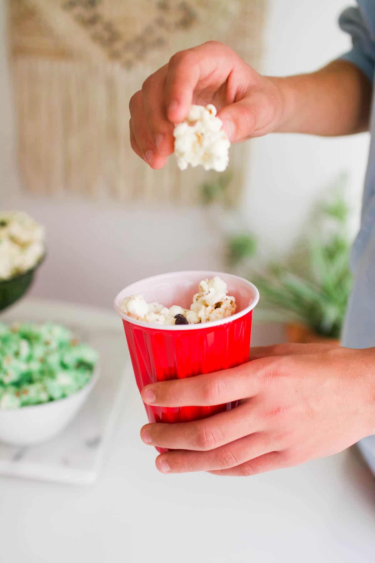 Kid eating white chocolate covered popcorn out of a red plastic cup.