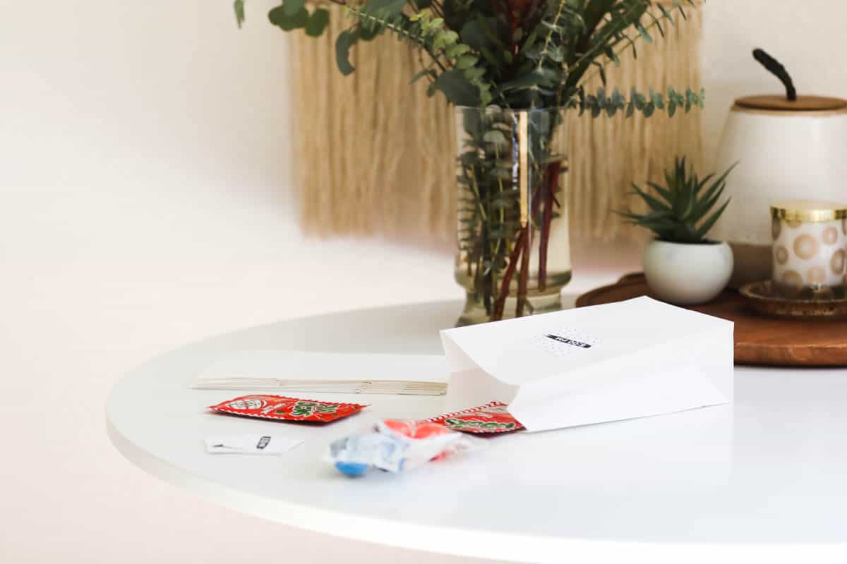 A paper bag laying on the table with small treats and toys coming out.