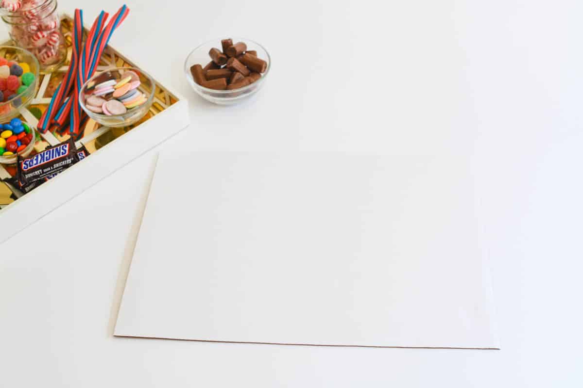 A cake board on a table next to some candy.