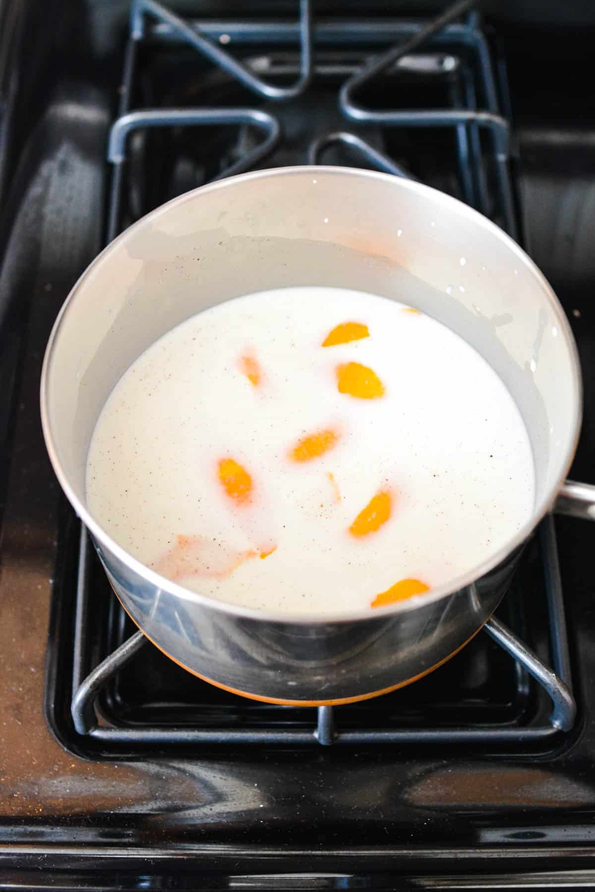 Saucepan of milk on the stove with orange peels in it.