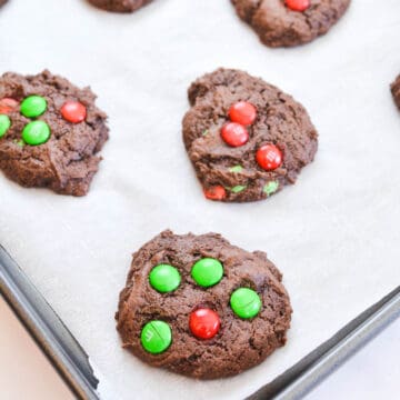 Baked Chocolate cookies with M&Ms on a cookie sheet.