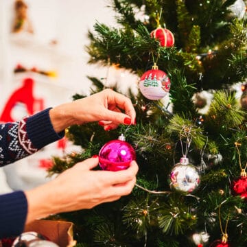 Close up of woman putting an ornament on a Christmas tree.