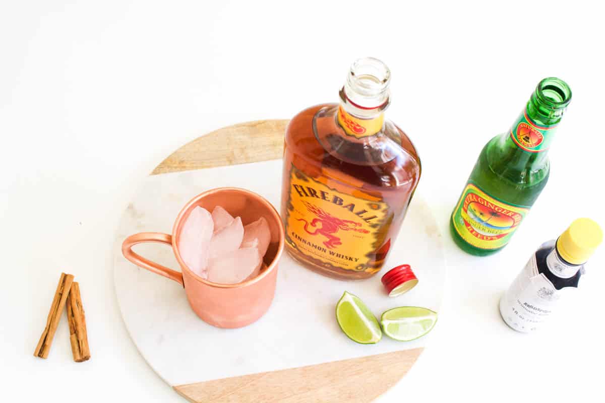 Overhead view of cocktail ingredients on a table next to a copper mug.