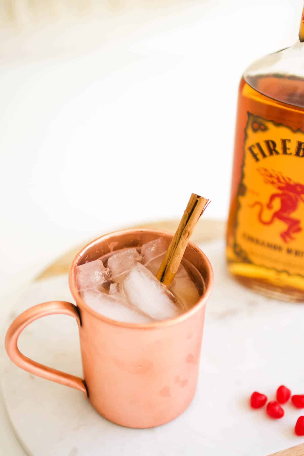 A copper moscow mule mug on a table next to a bottle of liquor.