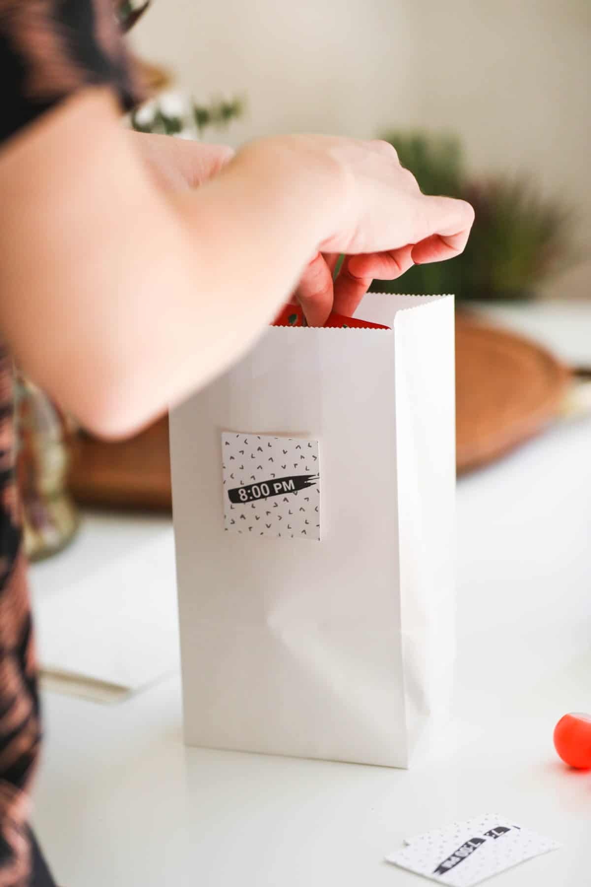 Woman adding small treats to hourly countdown bags for New Year's Eve.