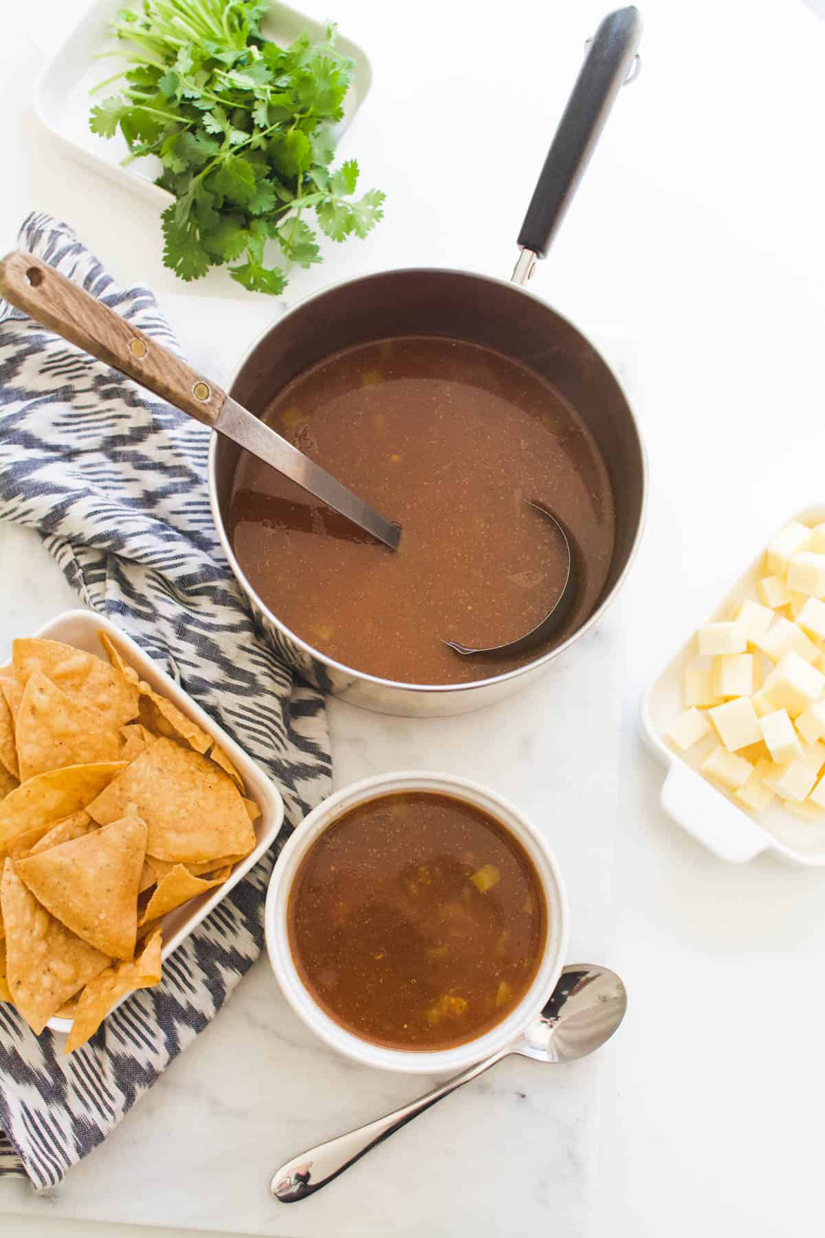 Pan of soup on a table with things to add to your bowl