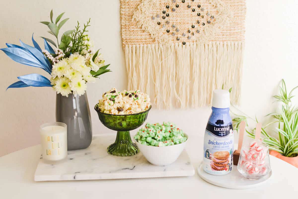 A party table with flowers and bowls of candy popcorn and coffee fixings.