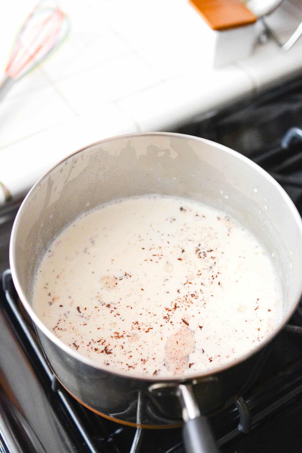 A saucpan on a stove with milk and chocolate melting in.