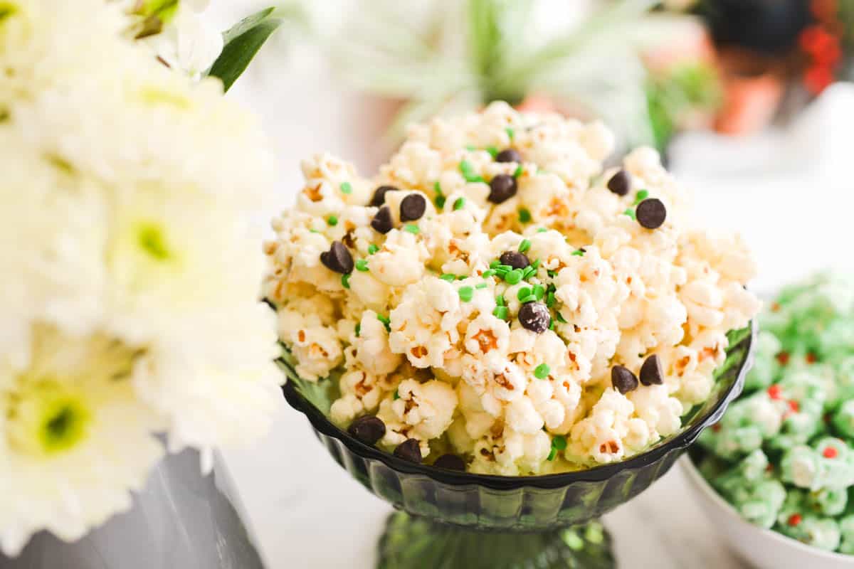 Close up of popcorn coated in white chocolate and topped with chocolate chips and colored sprinkles.