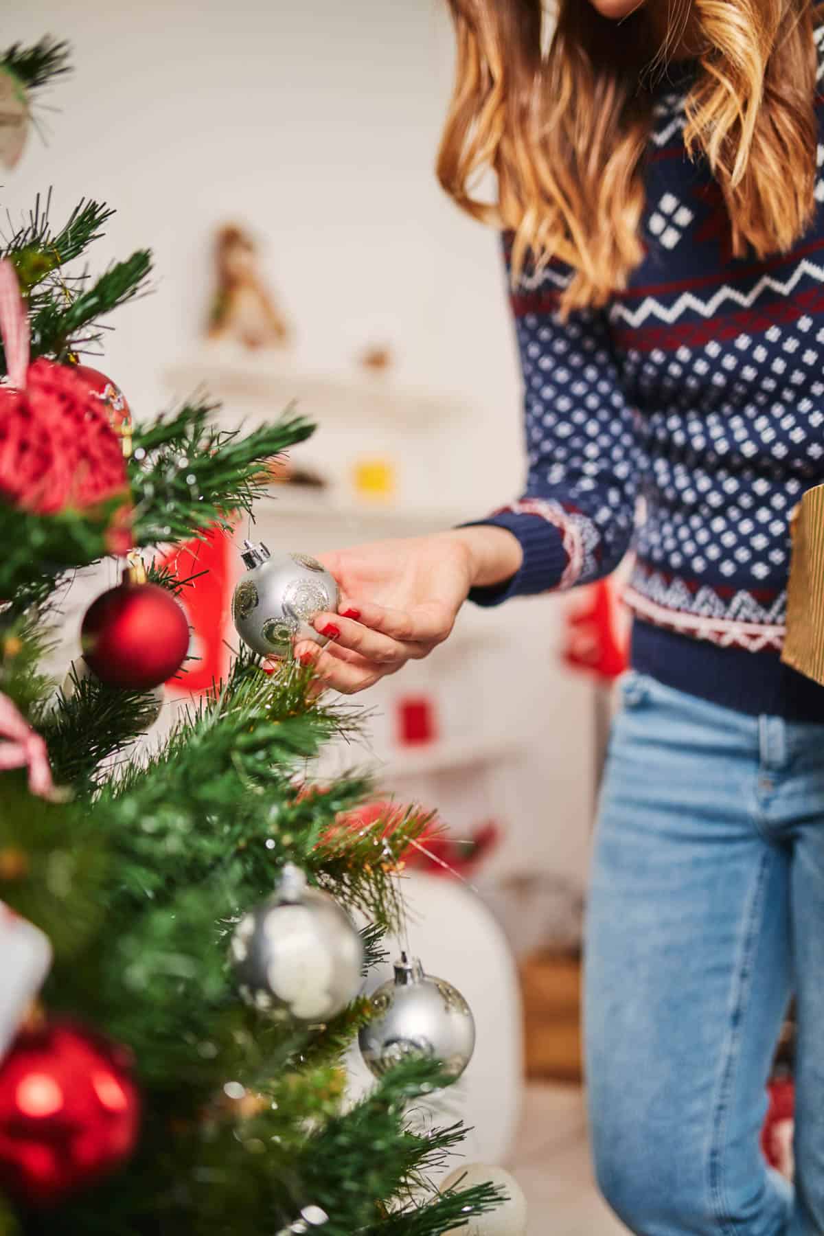 Woman touching an ornament on a Christmas tree.
