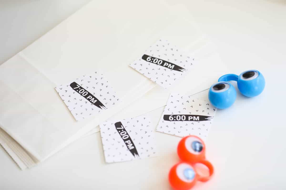 Paper bags and stickers with different times on them laying on a table.