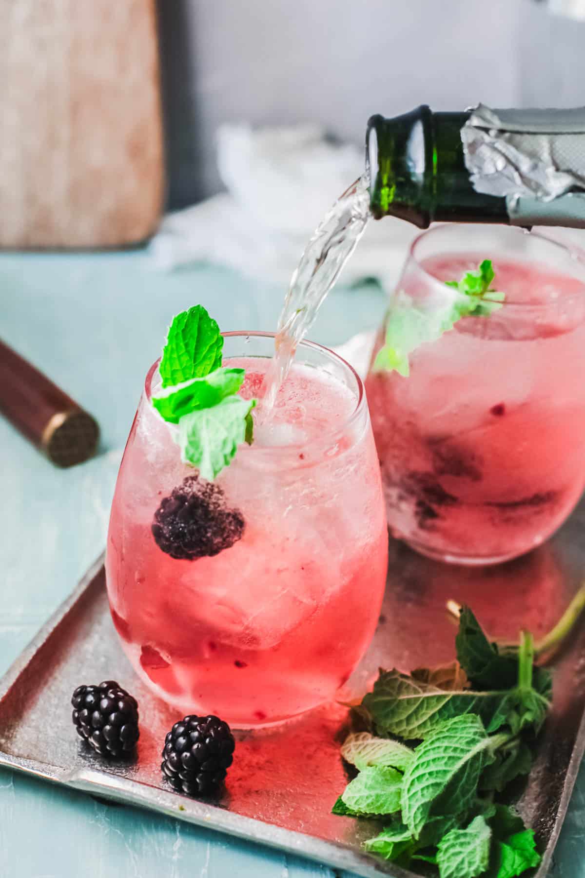 Pink cocktails on a table with champagne being added.