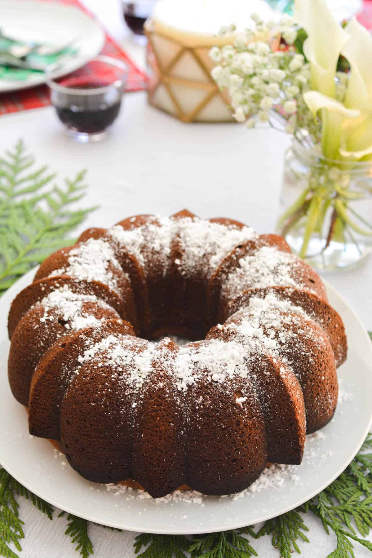 A bundt cake topped with powder sugar on a holiday table.
