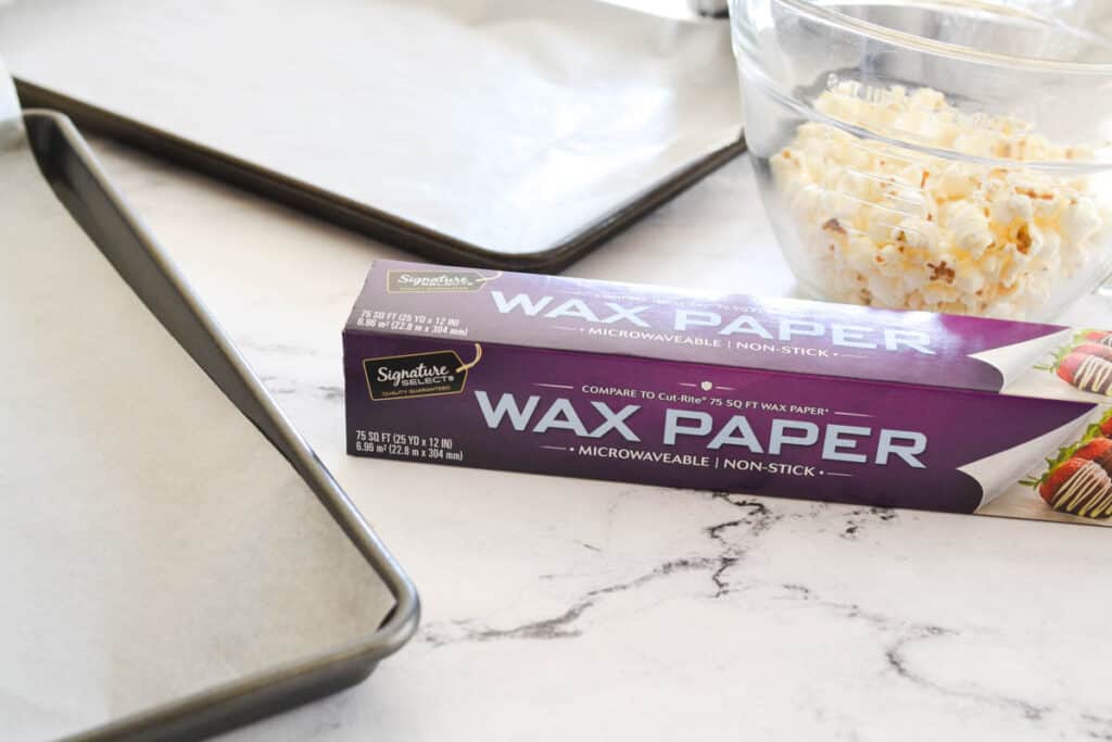 Box of wax paper on a counter between cookie sheets.