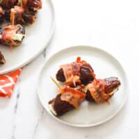 close up of bacon wrapped dates on an appetizer plate.