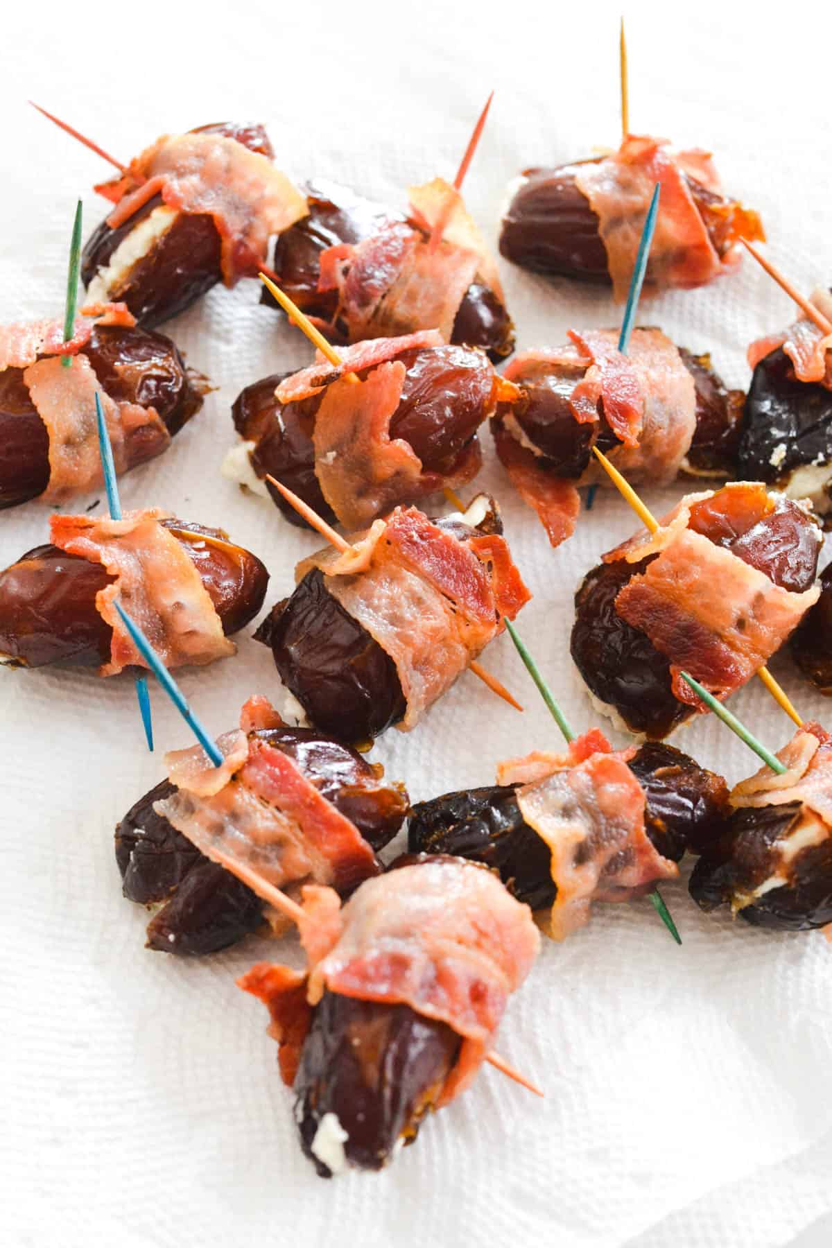 Close up of cooked bacon wrapped appetizers on a plate covered in paper towels.