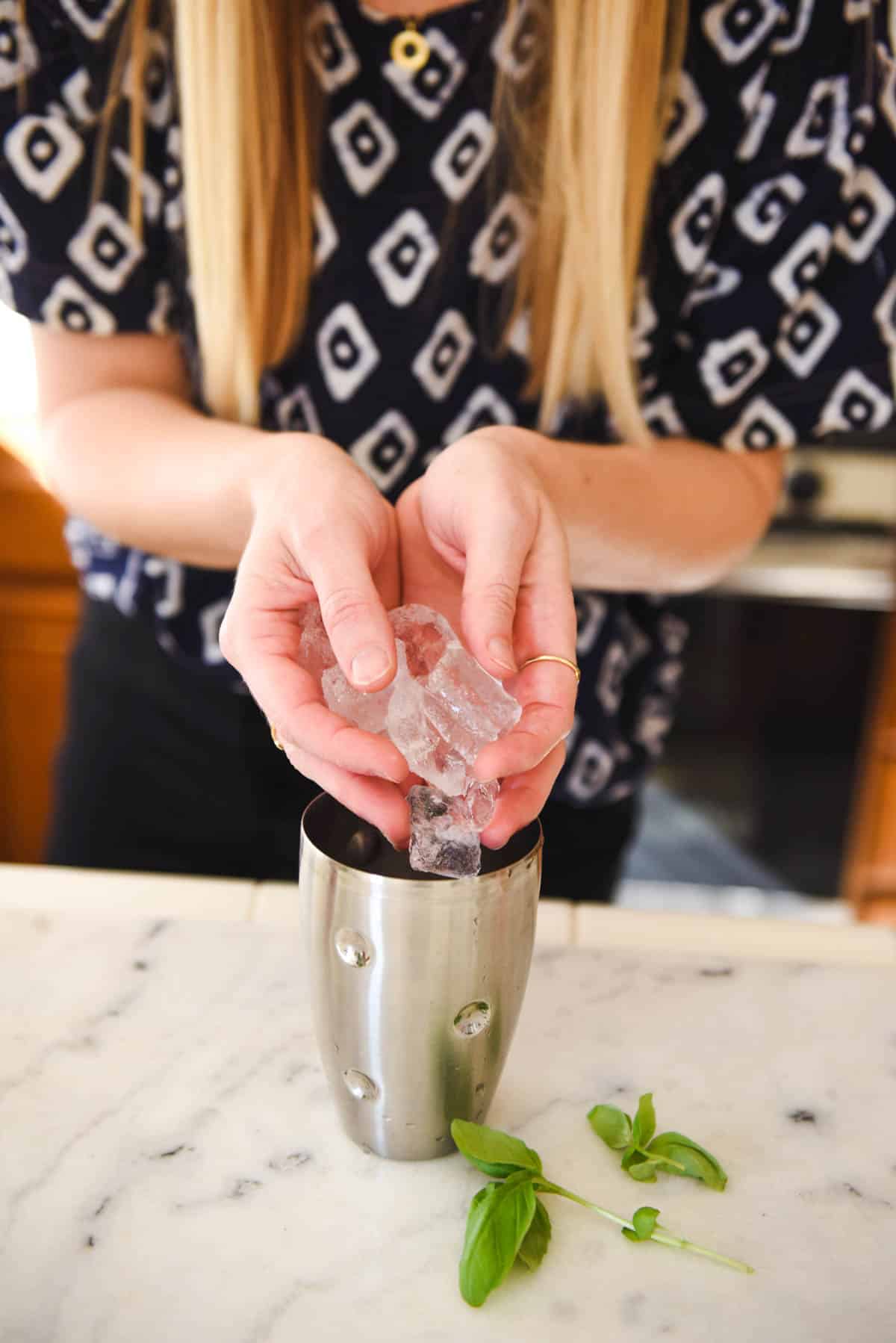 Woman adding ice to the cocktail shaker.