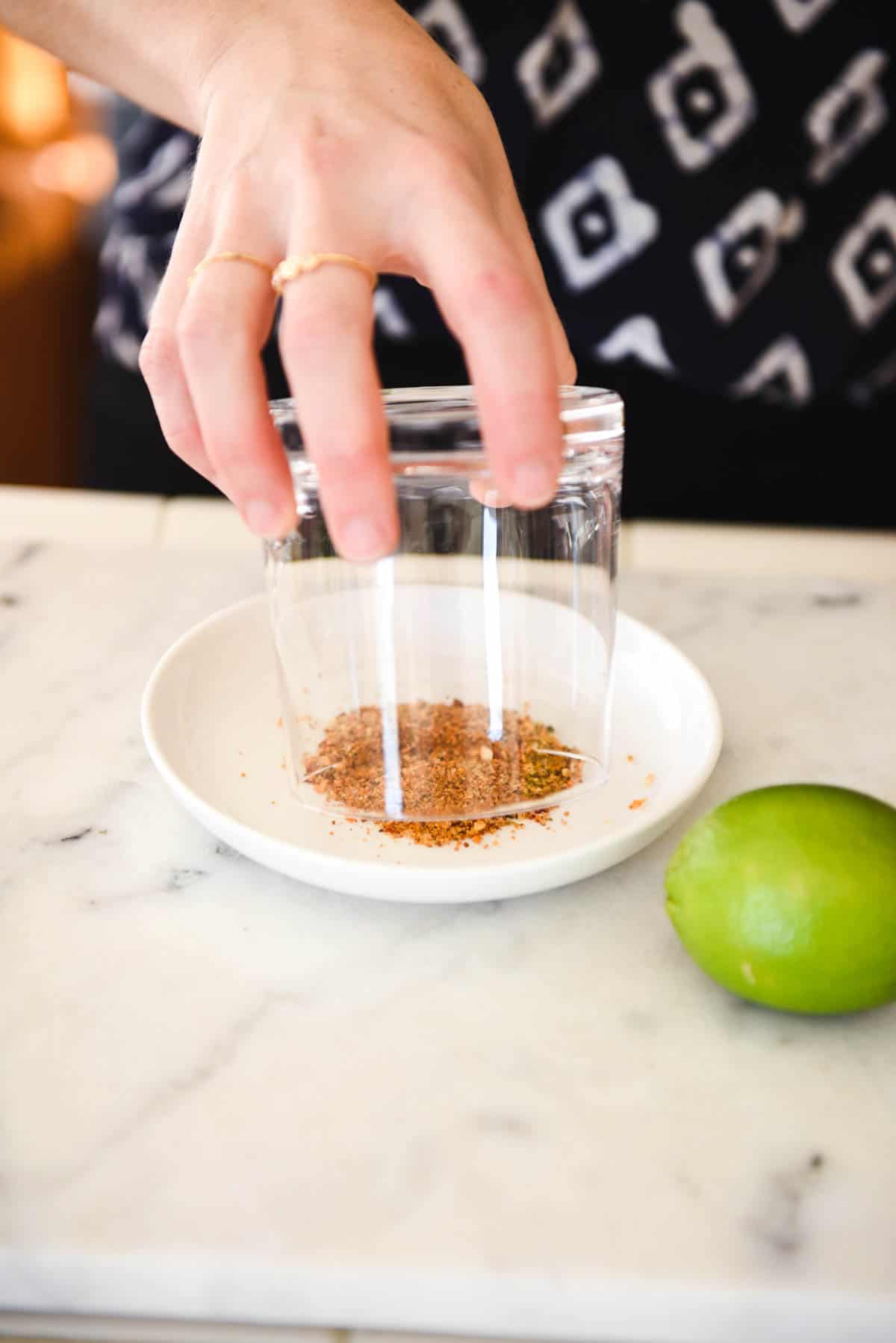 Woman adding a smoked sugar rim to a cocktail glass. 