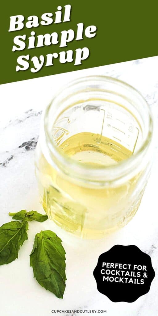 Close up of a jar with simple syrup on a table with fresh basil leaves laying next to it.