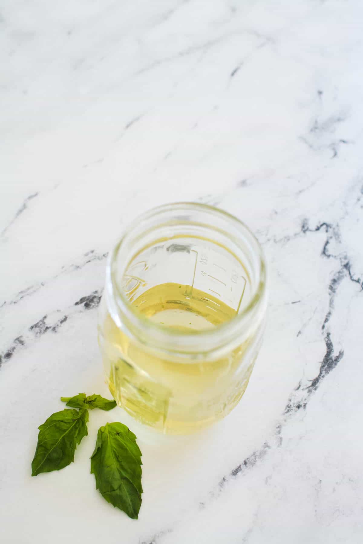 jar full of basil simple syrup recipe with extra basil leaves