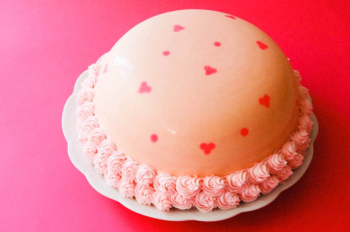 A white chocolate shell with pink hearts on it.