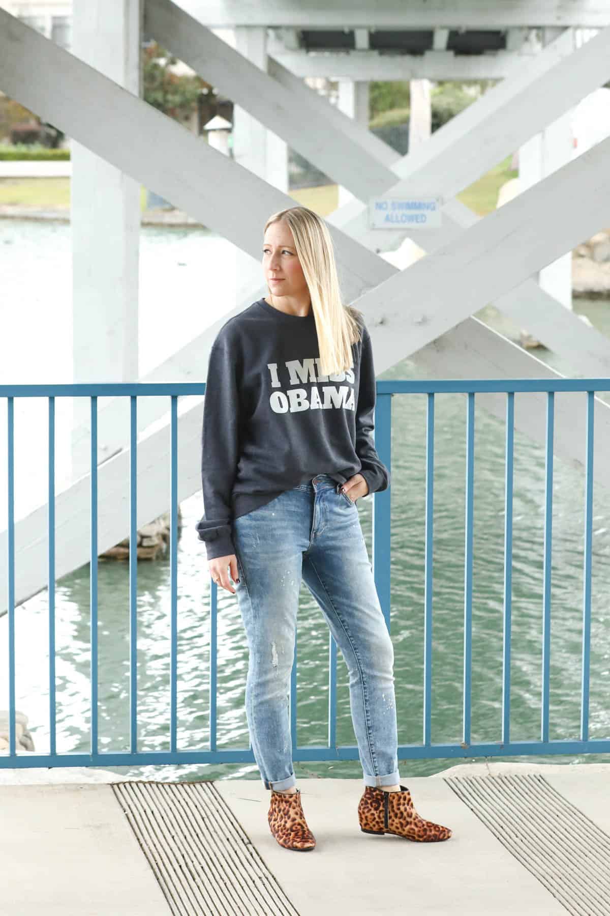Woman wearing a graphic crewneck sweatshirt with leopard booties.