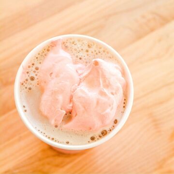 Top down image of flavored whipped cream on chocolate milk in a cup.