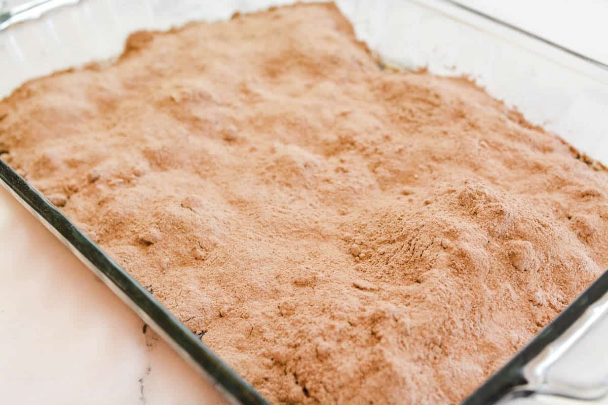 A baking dish on a counter with dry chocolate pudding powder spread out.
