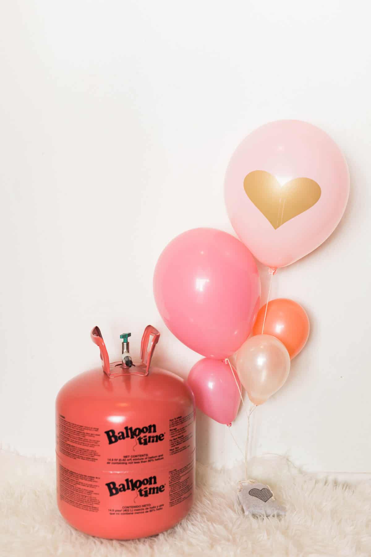 A helium tank next to a balloon bouquet for valentines day.