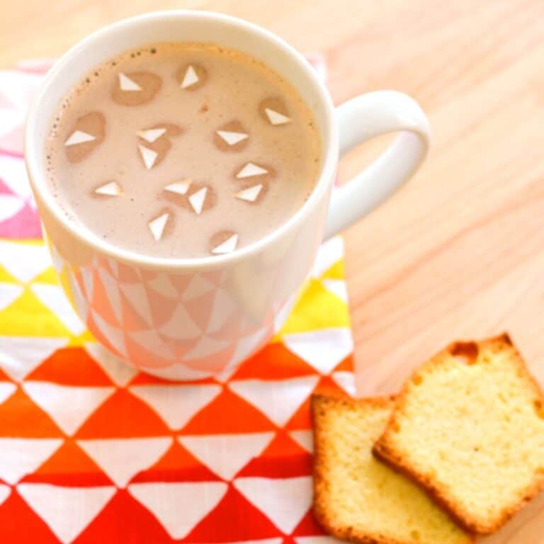 A cup of hot chocolate with triangle edible confetti floating in it.