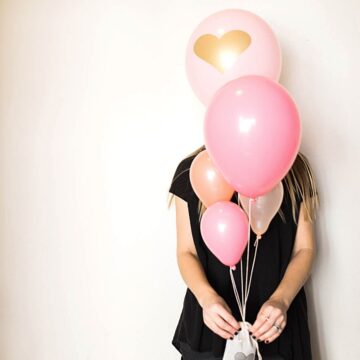 Woman holding a pink balloon bouquet with lavender sachet weight.