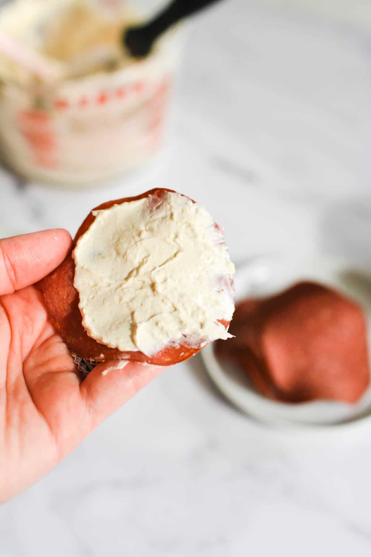 Holding a piece of dried beef spread with a cream cheese mixture.