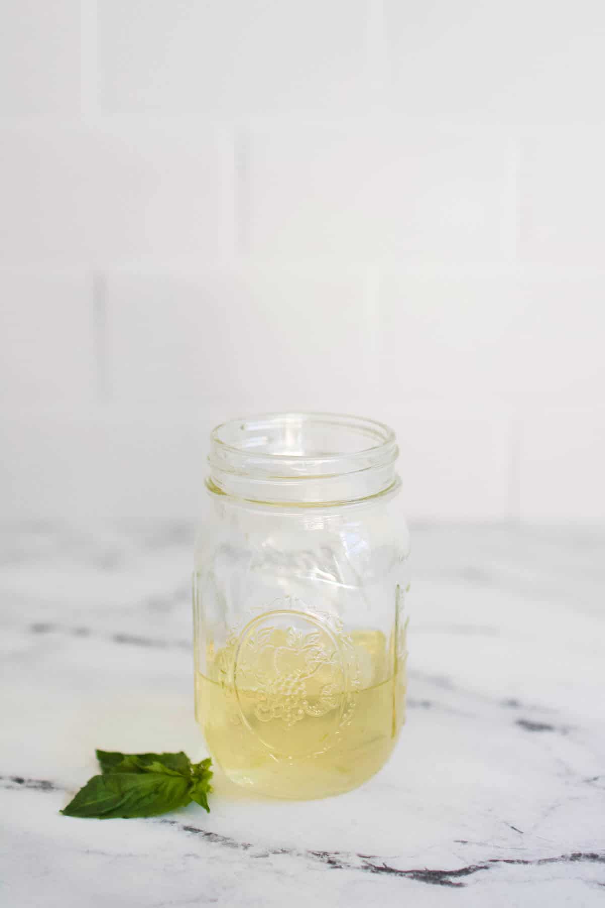 mason jar full of basil simple syrup on counter 