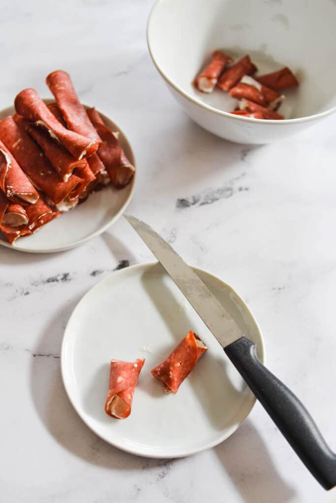 a beef roll up appetizer cut in half on a small plate.