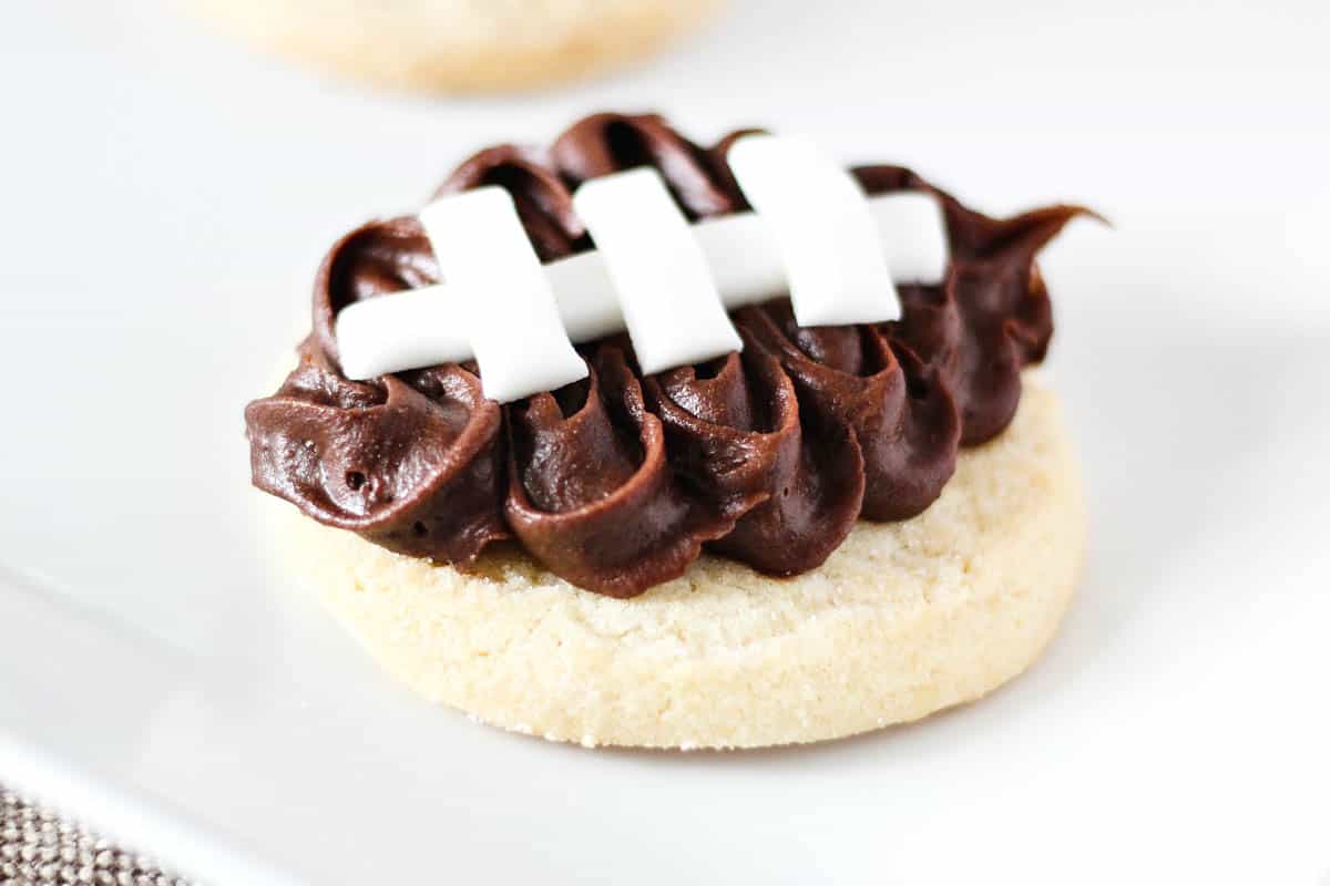 A close up of a sugar cookie frosted 
 with fondant to look like a football.