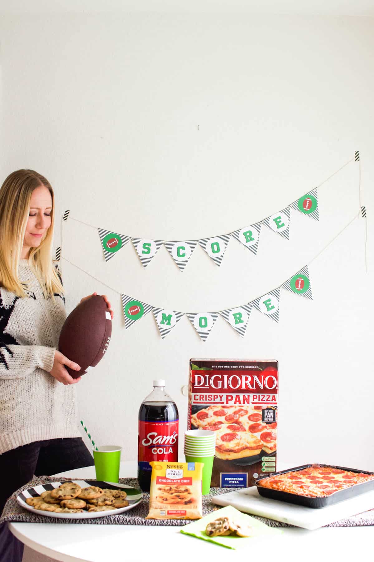 Woman holding football next to a printable banner for a football party.