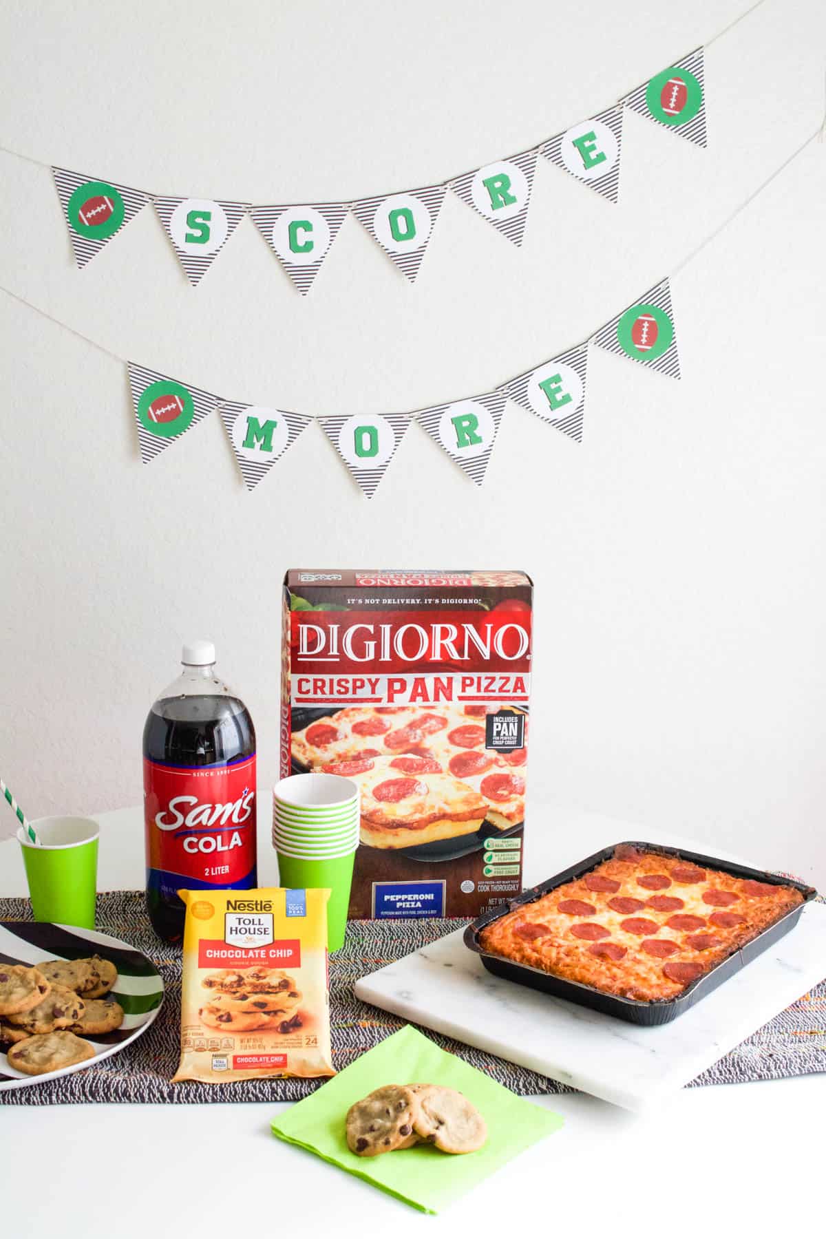 A printable football sign hung on a wall next to a party table.