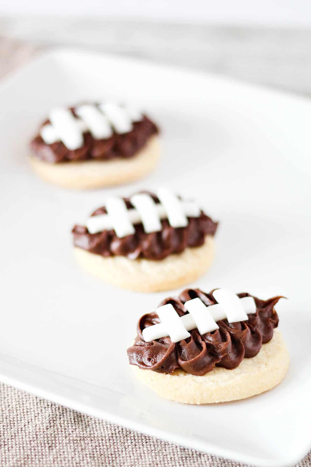 Football sugar cookies on a white platter.
