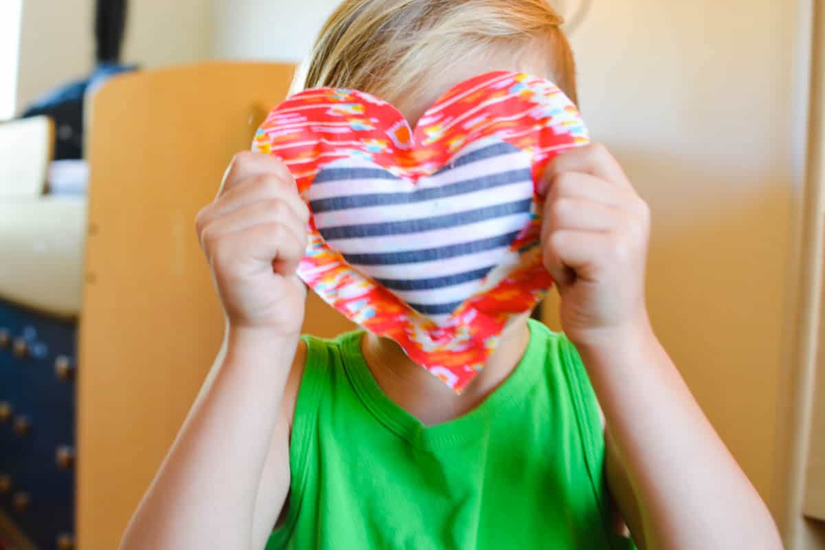 A kid holding a small heart pillow Valentine.
