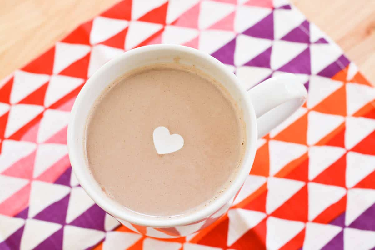 Close up of a heart shaped edible confetti floating on top of hot chocolate.