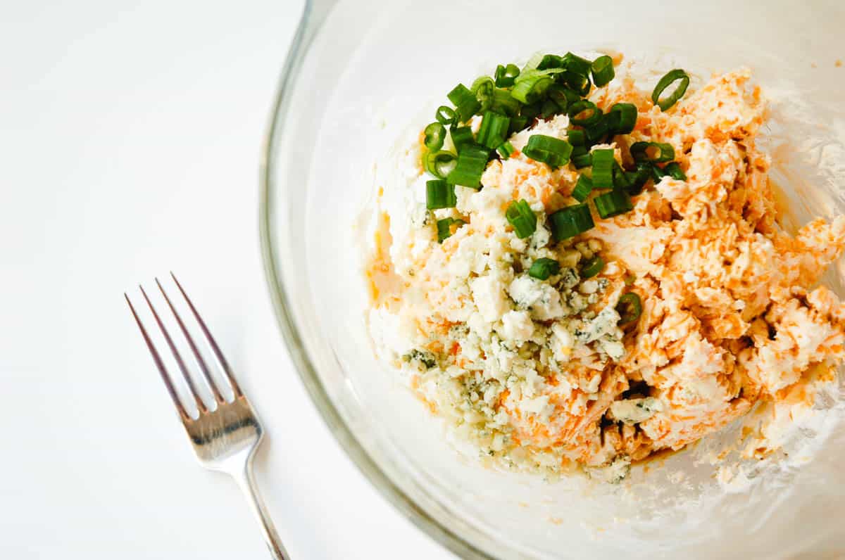 A bowl with ingredients for a cheddar and blue cheese cheese ball.